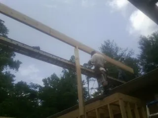 Carpenter setting a ridge beam over a new addition frame in Parksville