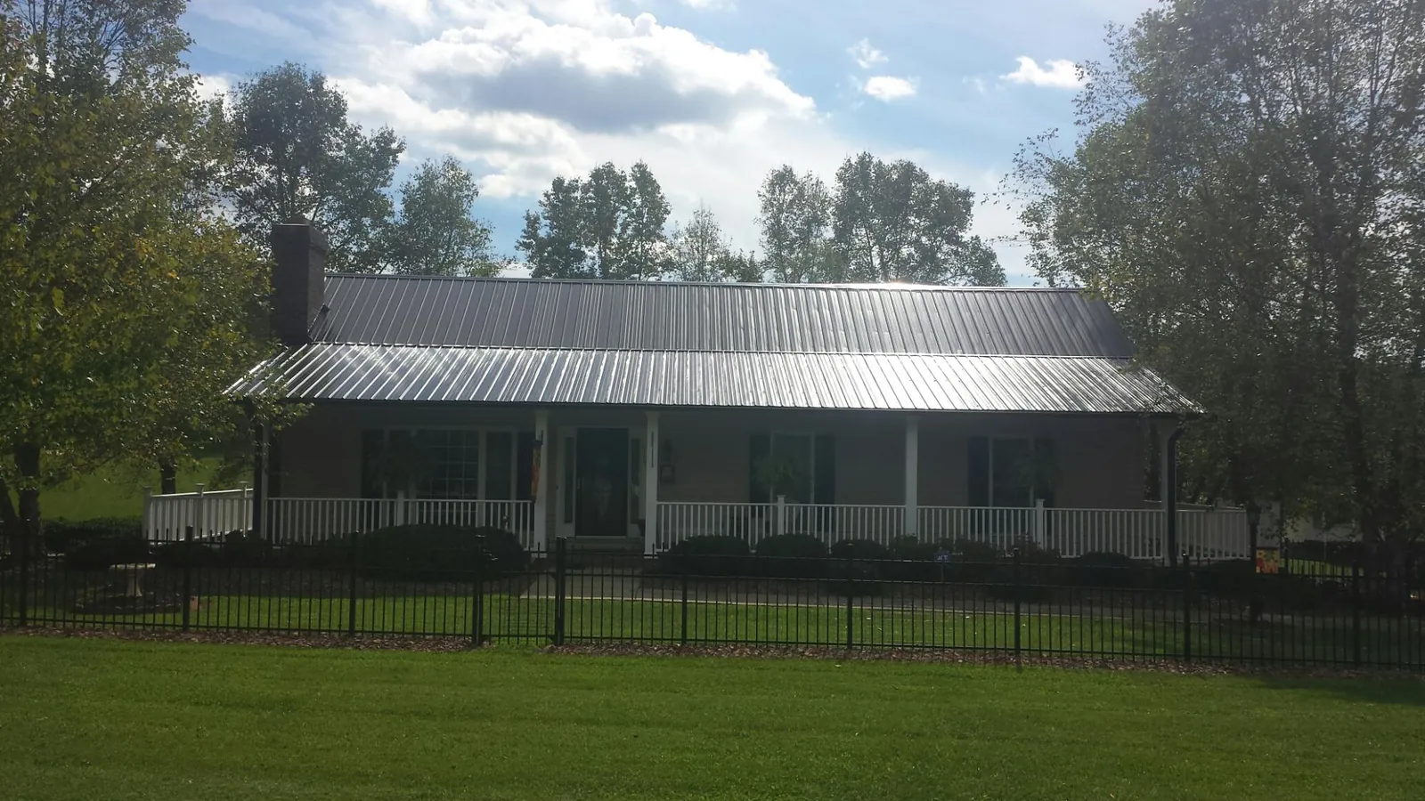Gray metal roof on a brick ranch with a full width front porch — Gutter Guard Installation work by our crew in Parksville