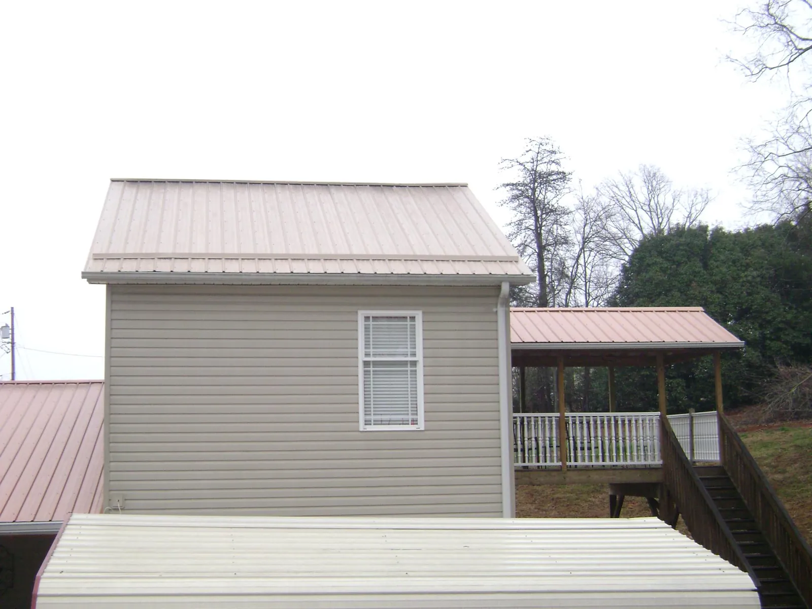 Tan metal roofs on a two story addition and attached porch, from a Roof Replacement job in Parksville