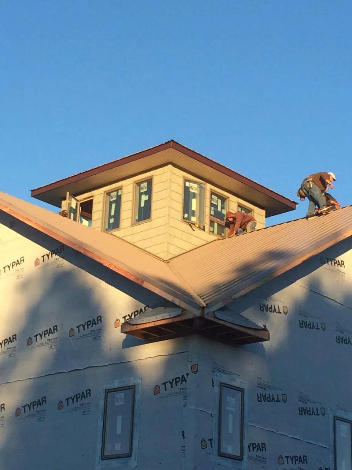 Roofers working around a rooftop cupola on a new metal roof at sunset — Roof Waterproofing in Parksville by Roofing Brothers